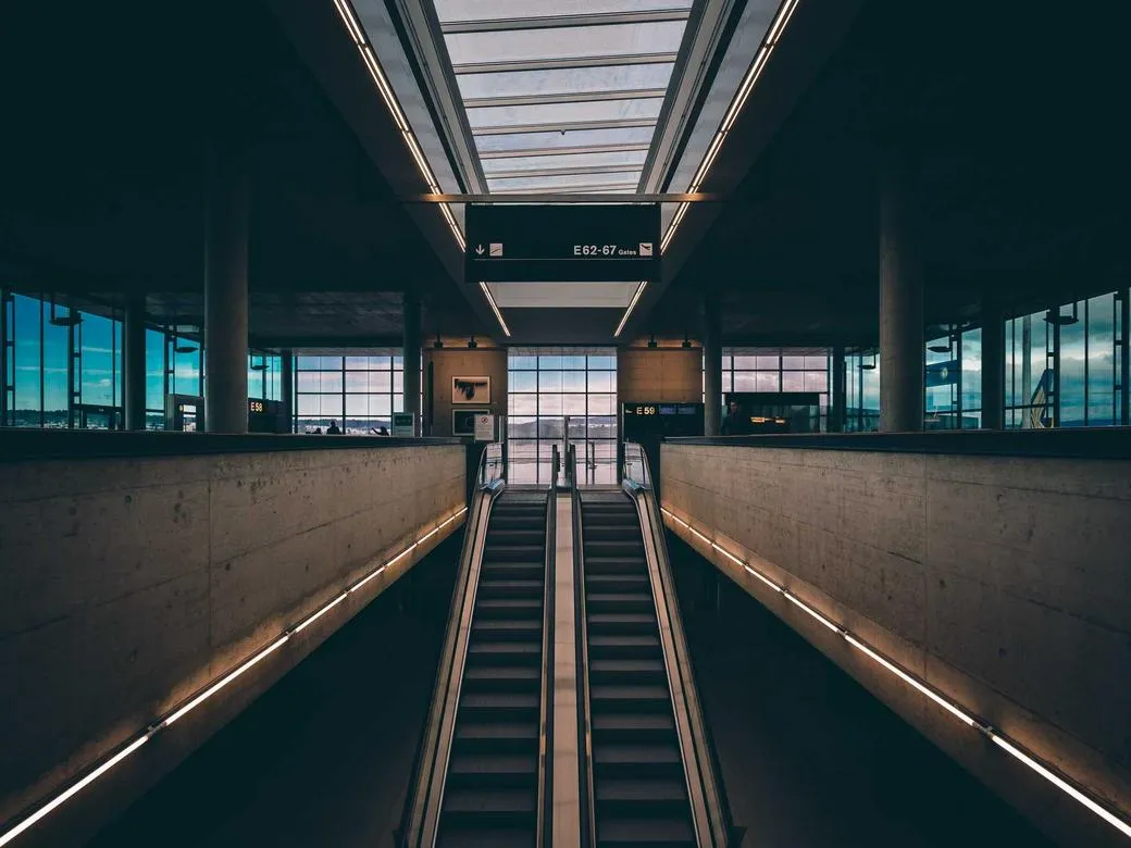 Twin escalators rising through a quiet, symmetrical concourse