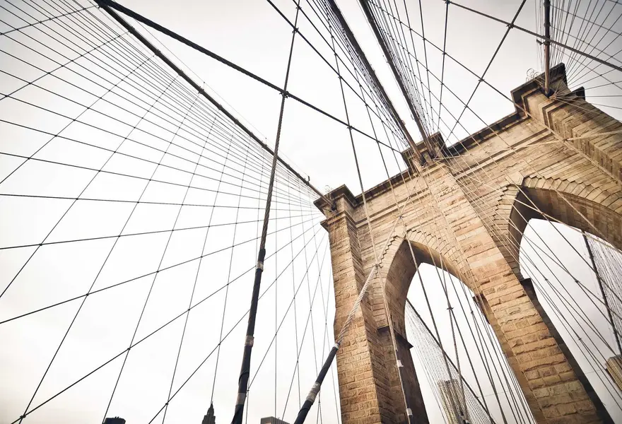 Steel cables of a suspension bridge fanning out from a stone tower